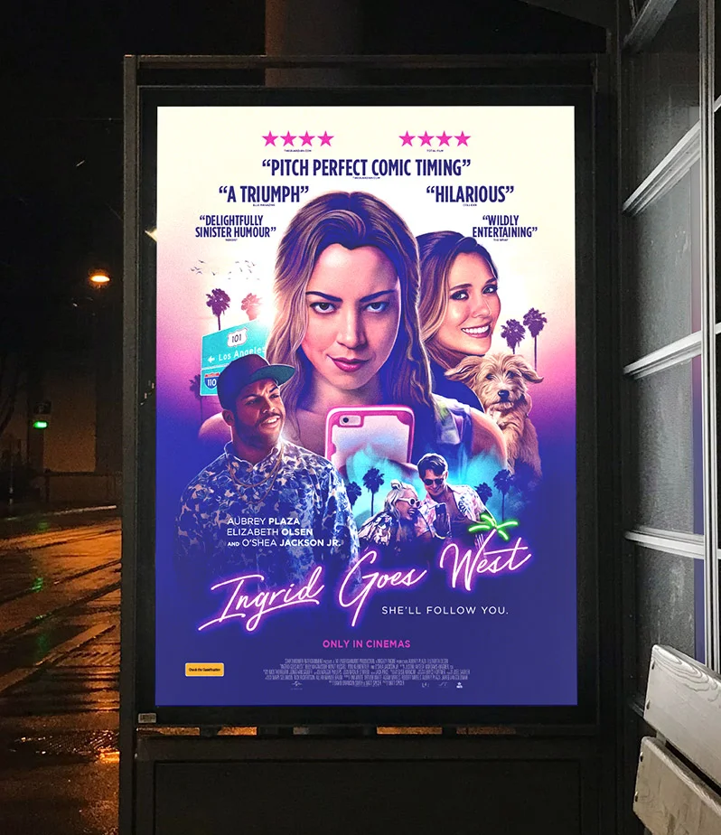 Side of bus stop at night lit up with large poster design for movie